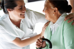 a caregiver and an old woman smiling at each other